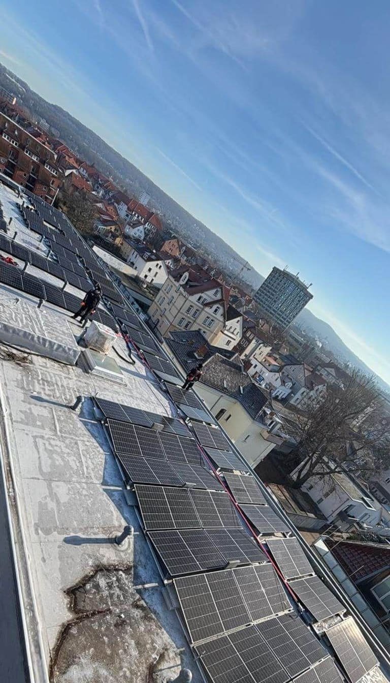 Langgestrecktes Flachdach eines Stadtgebäudes, über die volle Länge mit Solarmodulen belegt, dahinter die Dächer Göttingens