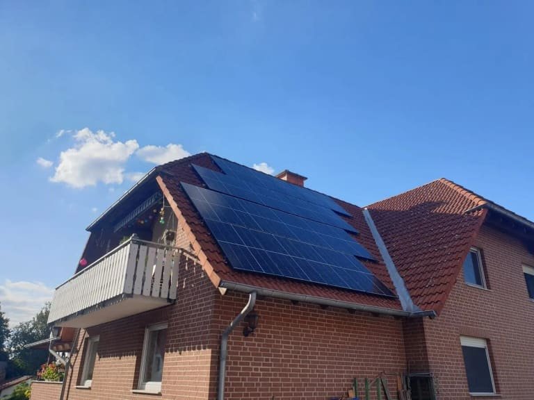 Backsteinhaus mit Balkon, Solarmodule auf beiden Dachflächen